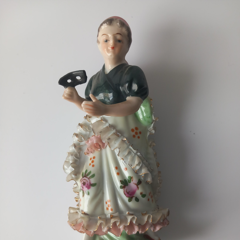 figurka porcelanowa owczarek niemiecki copy Zbliżenie na czarną maskę trzymaną przez porcelanową figurkę.
