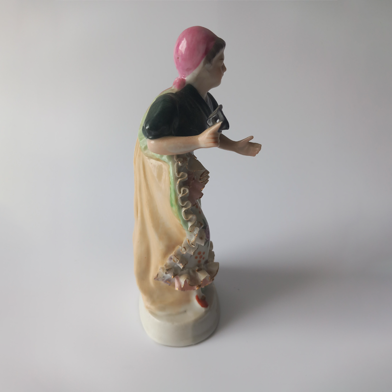 figurka porcelanowa owczarek niemiecki copy Lewy profil figurki porcelanowej, widoczne ręcznie malowane kwiaty i złocenia na sukni.