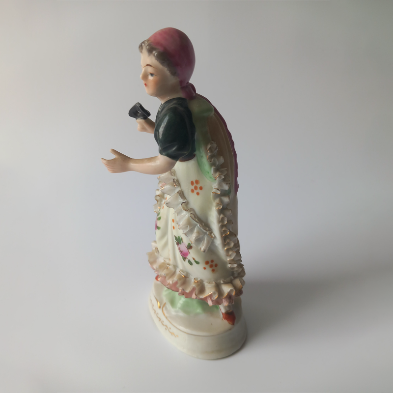 japońska figurka porcelanowa „dama z maską” Prawy profil figurki porcelanowej, widoczne ręcznie malowane kwiaty i złocenia na sukni.