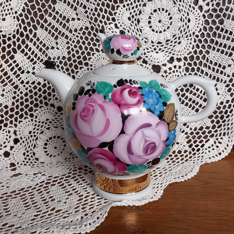 Ozdobny imbryk porcelanowy z kwiatowym wzorem i złoceniami na szydełkowej serwetce. Ozdobny imbryk porcelanowy z kwiatowym wzorem i złoceniami na szydełkowej serwetce.