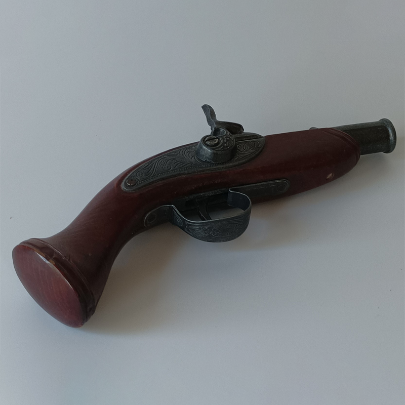 Kieszonkowy Pistolet Skałkowy – Ozdobna Replika Historyczna (23 cm) Krótka, dekoracyjna replika pistoletu skałkowego z ciemnorudym łożem i rzeźbionym metalowym zamkiem.