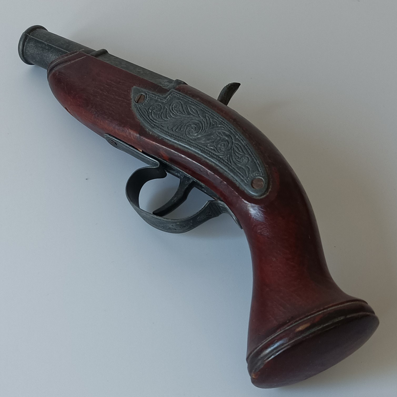 Kieszonkowy Pistolet Skałkowy – Ozdobna Replika Historyczna (23 cm) Lewa strona repliki krótkiego pistoletu, widoczna metalowa blaszka z bogatym ornamentem kwiatowym i kabłąk.