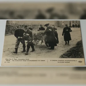 Czarno-biała pocztówka z 1914 roku przedstawiająca belgijskiego kapelana i żołnierzy transportujących rannego na wózku.