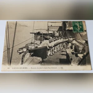 Zabytkowa pocztówka z 1909 roku przedstawiająca francuskich marynarzy ćwiczących z karabinami na pokładzie krążownika.